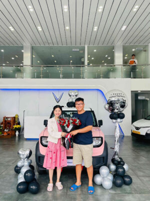 Khách hàng chụp hình tại đại lý Vinfast Bình Chánh với xe điện màu hồng.